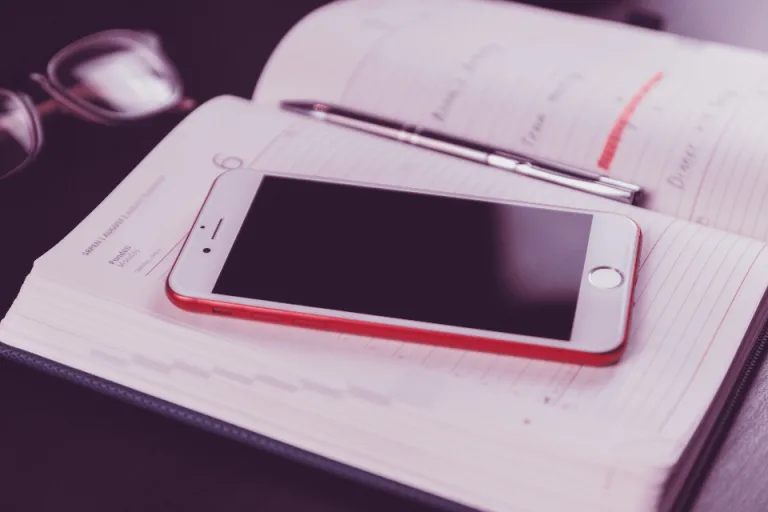 Smartphone resting on an open planner with a pen
