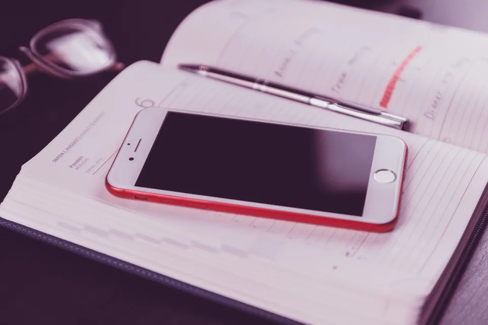 Smartphone resting on an open planner with a pen