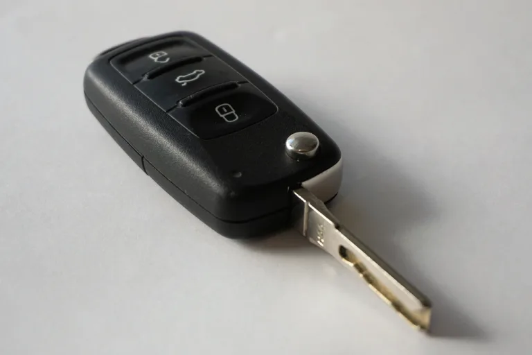 A black car key lying on a plain light gray surface