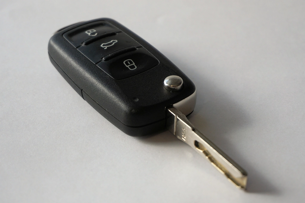 A black car key lying on a plain light gray surface