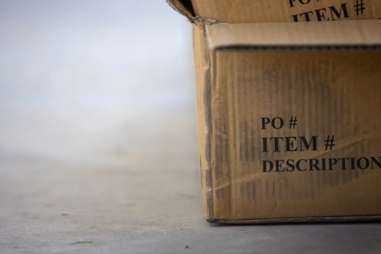 A plain cardboard shipping box sitting on a gray floor