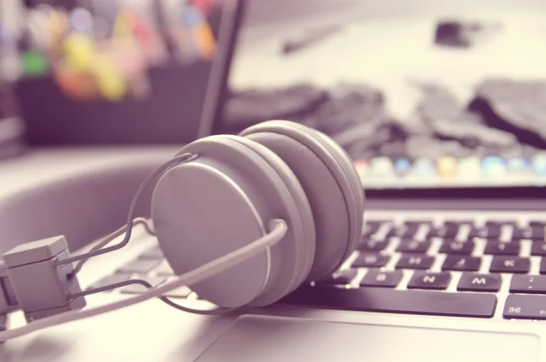 White headphones resting on an open laptop keyboard