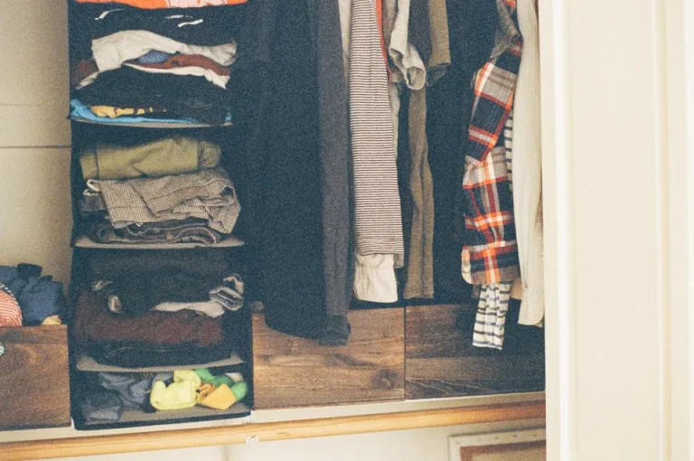 An open closet with neatly folded clothes on shelves and shirts on hangers