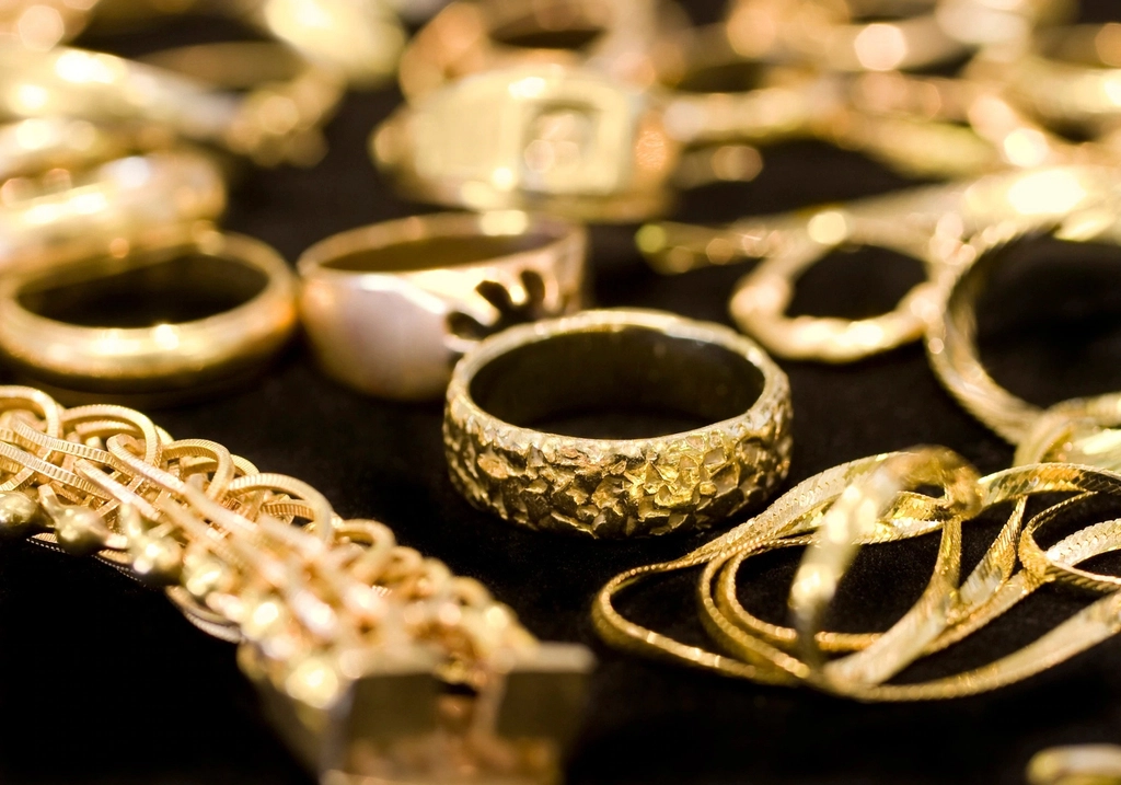 A close-up of gold rings, bracelets and chains on a dark cloth