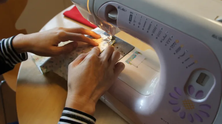 Hands guiding fabric through a home sewing machine